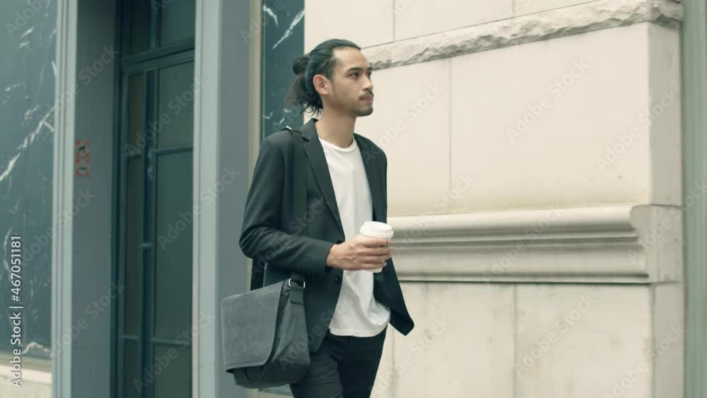 Young Asian businessman casual dress holding coffee cup during walking in the street to the office in the morning. Young Asian businessman casual dress holding coffee cup during walking in the street to the office in the morning.