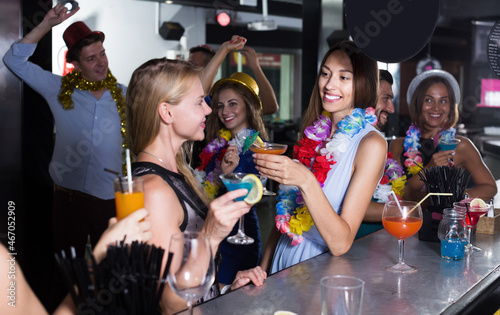 Smiling women have fun and drinking cocktails on hawaiian party.