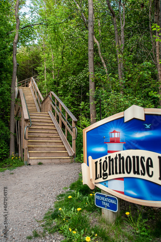 A wooden staircase leads up a hill through a forest at the bottom of the Lighthouse Trail in Goderich, Ontario, leading to the town's historic lighthouse. photo