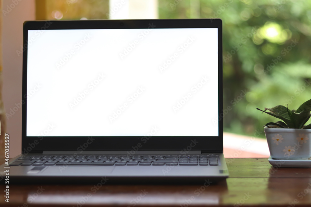 Fototapeta premium Close-up view of open blank screen laptop computer on wood table.