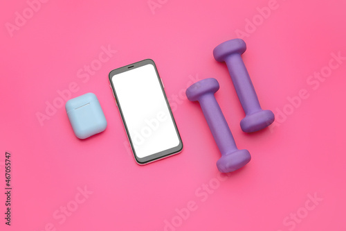 Dumbbells, mobile phone and earphones on pink background © Pixel-Shot