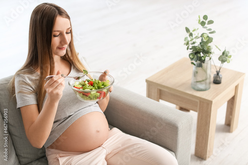 Young pregnant woman eating...