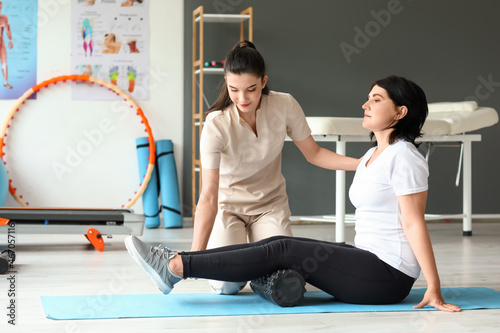 Mature woman training with physiotherapist on mat in rehabilitation center