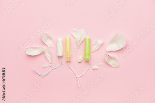 Menstrual tampons and flower petals on pink background