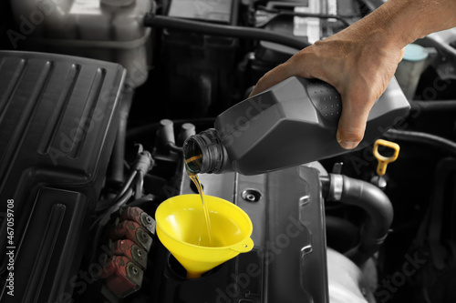 Male mechanic pouring motor oil from canister into car engine © Pixel-Shot