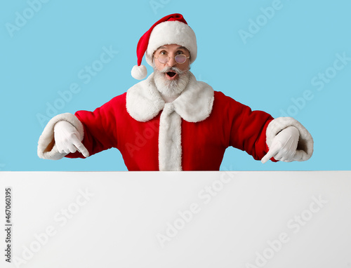 Santa Claus with blank poster showing something on color background