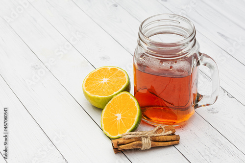 Black tea in a glass jar, lemon, cinnamon on a white wooden background. Copy space