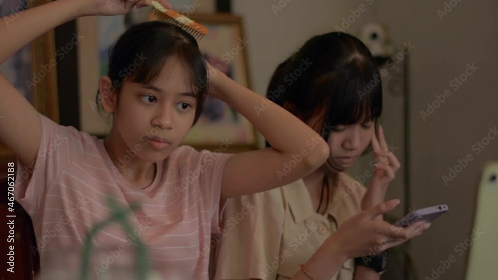 Two Asian teen girls styling hair and searching useful information from website on smartphone before doing live streaming on social media online with digital device at home. Young lifestyle. Two Asian teen girls styling hair and searching useful information from website on smartphone before doing live streaming on social media online with digital device at home. Young lifestyle.