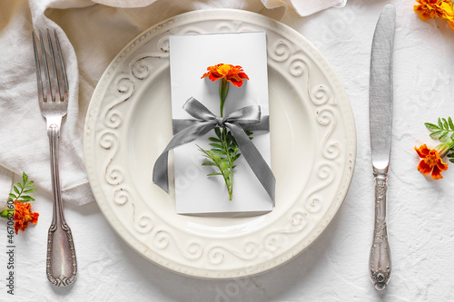 Beautiful table setting with marigold flowers on light background