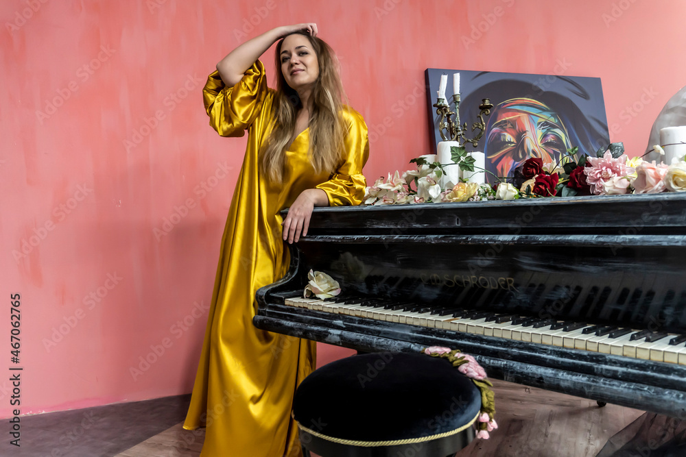 young beautiful woman near the piano in a gold dress young beautiful woman near the piano in a gold dress