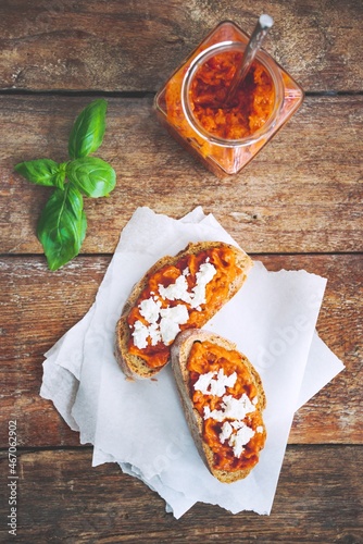 Obraz na płótnie Wholegrain bread covered with tomato-pepper dip and feta cheese over old rustic wooden table. Homemade organic vegetable dish. w salonie