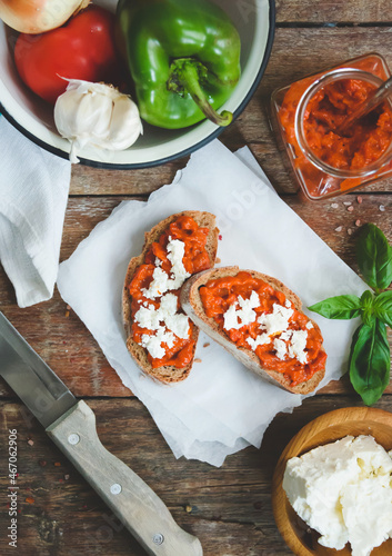 Obraz na płótnie Wholegrain bread covered with tomato-pepper dip and feta cheese over old rustic wooden table. Homemade organic vegetable dish. w salonie