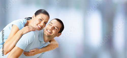 Happy amazed smiling couple. Portrait of standing close embracing, piggyback pose models in love concept, indoors. Brunette man and woman together. Copy space area.