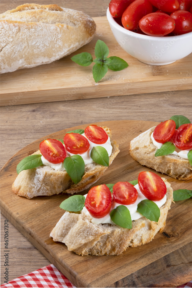 Italian bruschetta with roasted tomato, cheese cream, basil and herbs, selective focus.