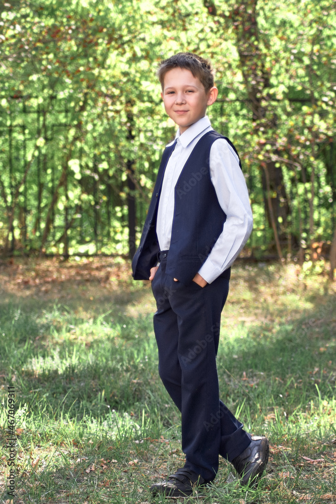 Portrait of a schoolboy looking into the camera on a blurry background of green trees. Portrait of a schoolboy looking into the camera on a blurry background of green trees.