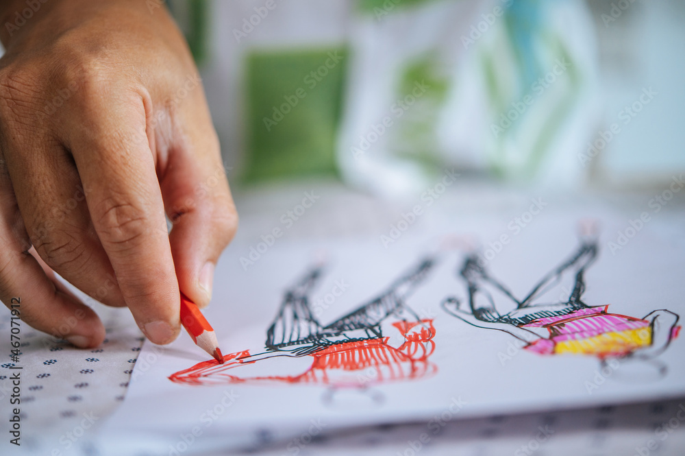 Close up hand of female designer drawing clothes sketches Close up hand of female designer drawing clothes sketches