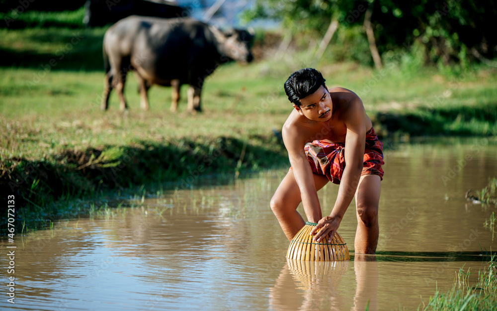 Fototapeta premium Asian young man in loinclothes and bamboo fishing trap
