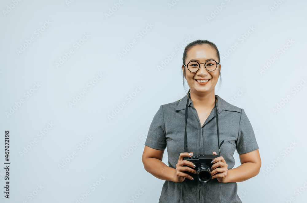 Portrait of Asian woman glasses wearing casual clothes with a big smile on face, holding a camera taking a picture. Isolated background in studio with blank space. Portrait of Asian woman glasses wearing casual clothes with a big smile on face, holding a camera taking a picture. Isolated background in studio with blank space.