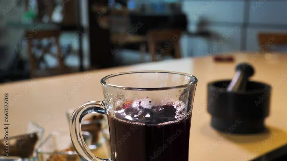 Putting cinnamon stick in glass of hot mulled wine Putting cinnamon stick in glass of hot mulled wine