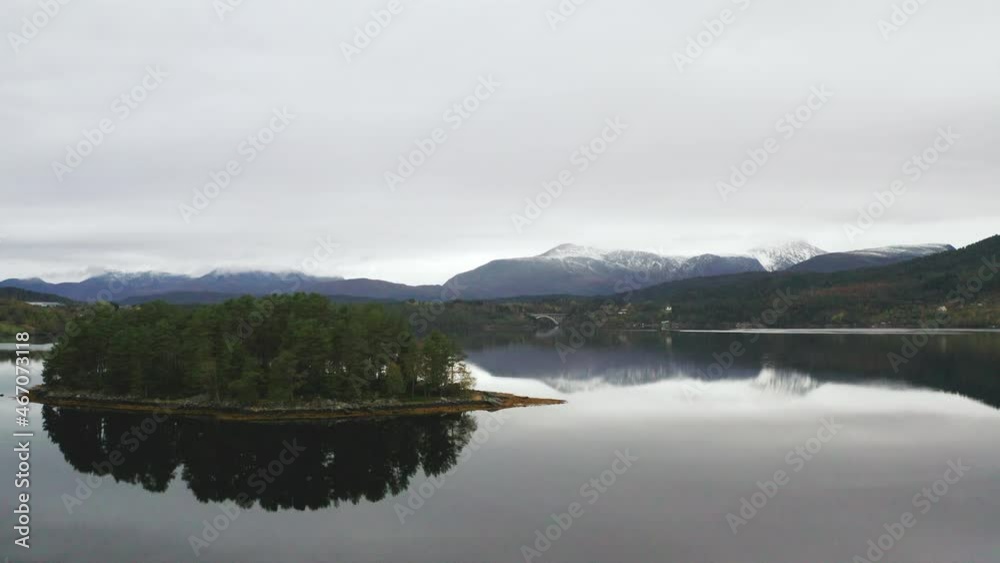 Mirror Reflection On Serene Seascape Surrounded With Hills And Snowcapped Mountains In Norway. Aerial Drone Mirror Reflection On Serene Seascape Surrounded With Hills And Snowcapped Mountains In Norway. Aerial Drone