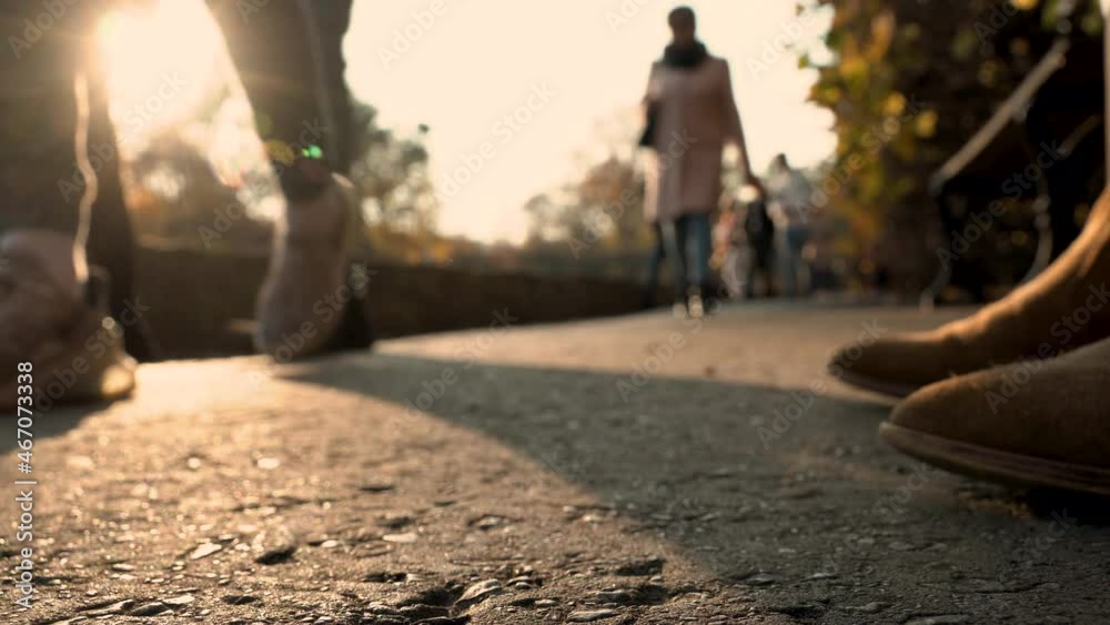 Low angle shot of people walking outdoors on promenade during sunset in background - Cold autumn day - Close up of shoes,person sitting on bench Low angle shot of people walking outdoors on promenade during sunset in background - Cold autumn day - Close up of shoes,person sitting on bench