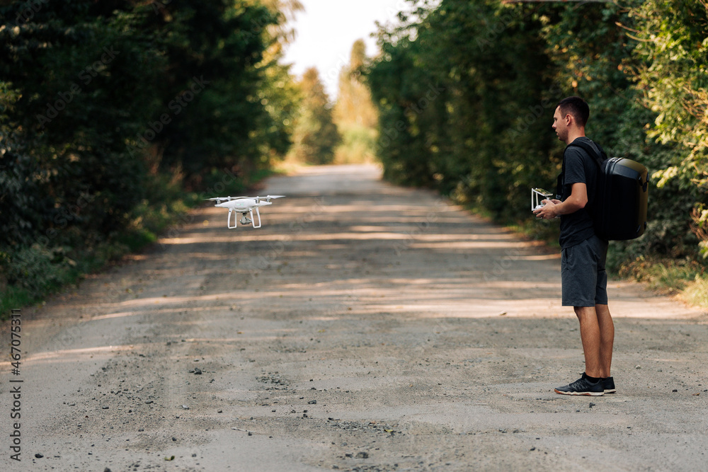 Fototapeta premium man flying a drone in road. Young Man navigating a flying drone