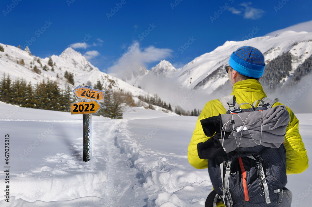 2022 and 2021  written on a postsign with a hiker walking on the snow in a mountain