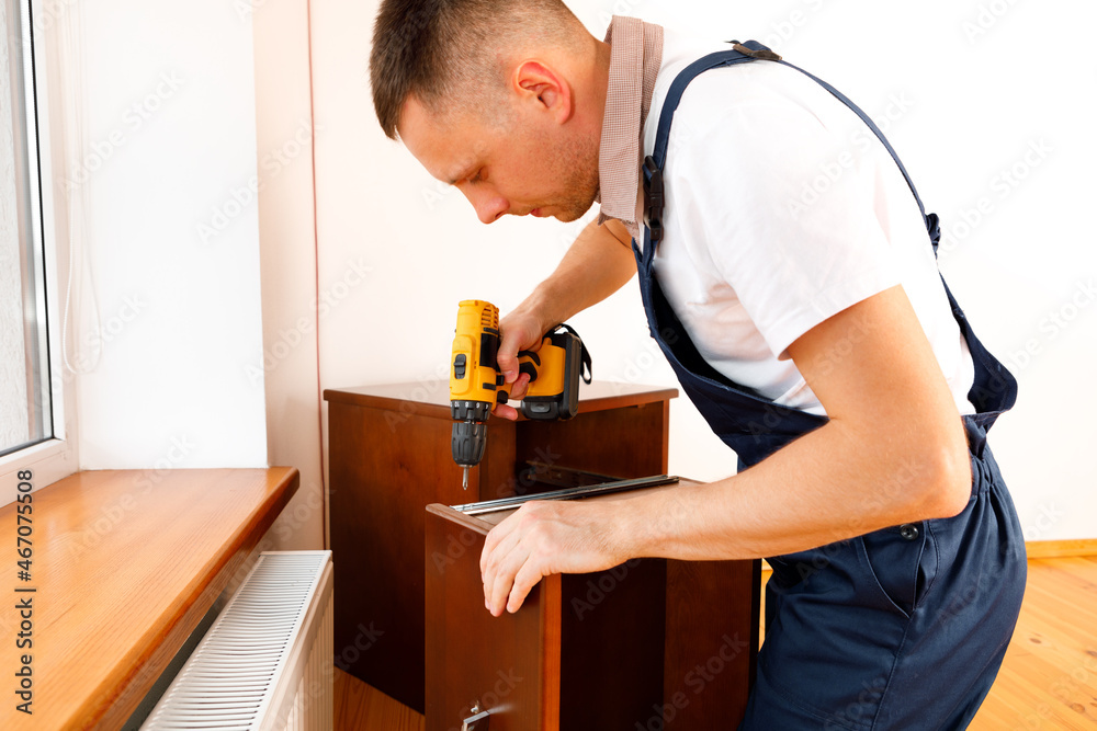 Handyman in blue uniform works with electricity automatic screwdriver. House renovation conception. Handyman in blue uniform works with electricity automatic screwdriver. House renovation conception.