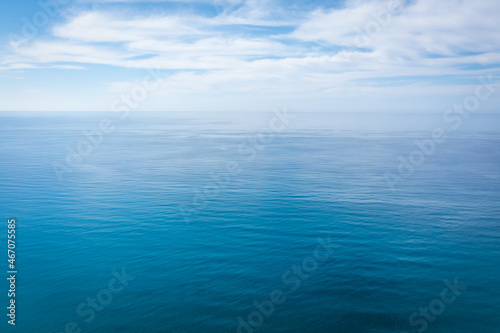 Closeup surface of calm ocean blue sea water with day light and clouds. Abstract Background Texture.