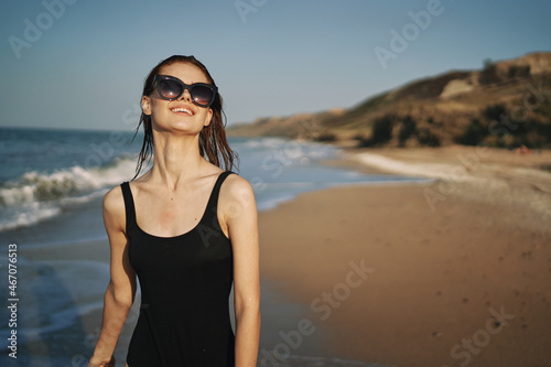 woman walks along the sandy shore in a black swimsuit sun tropics