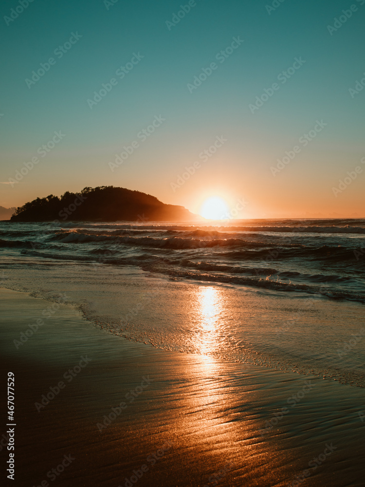 Sunrise on the beach and ocean waves.