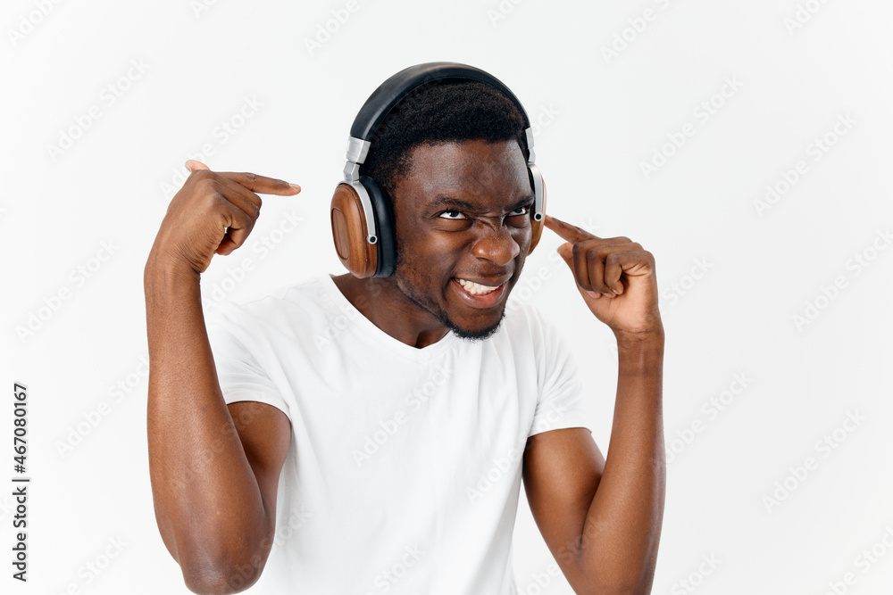 man of african appearance in headphones in a white t-shirt listening to music man of african appearance in headphones in a white t-shirt listening to music