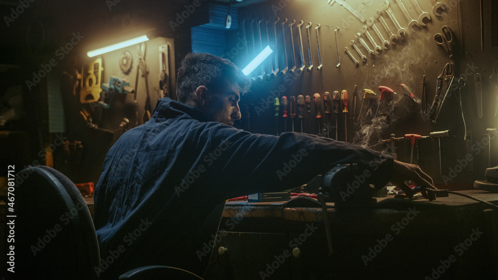 Young blacksmith man with workwear, taking solder tool, sitting on chair and do solder. Young blacksmith man with workwear, taking solder tool, sitting on chair and do solder.