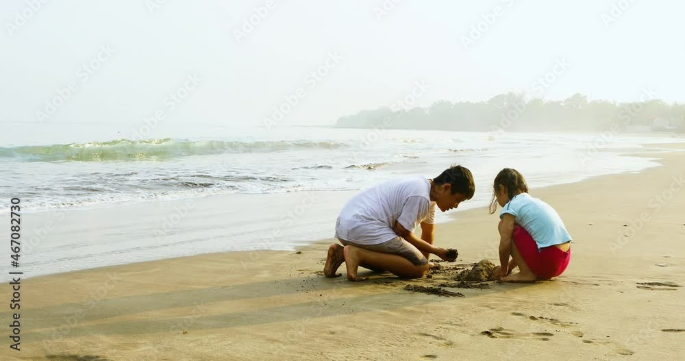 Two happy kids playing sand on the beach Two happy kids playing sand on the beach