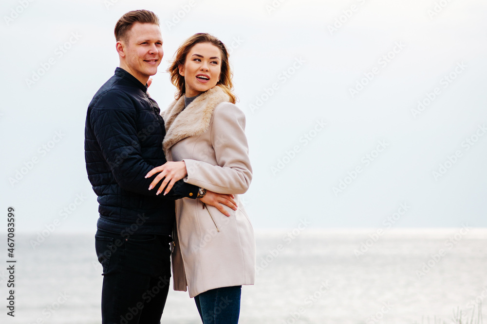 Portrait of pretty young couple wearing trendy spring clothes. Two lovers posing against beach background in evening. Portrait of pretty young couple wearing trendy spring clothes. Two lovers posing against beach background in evening.