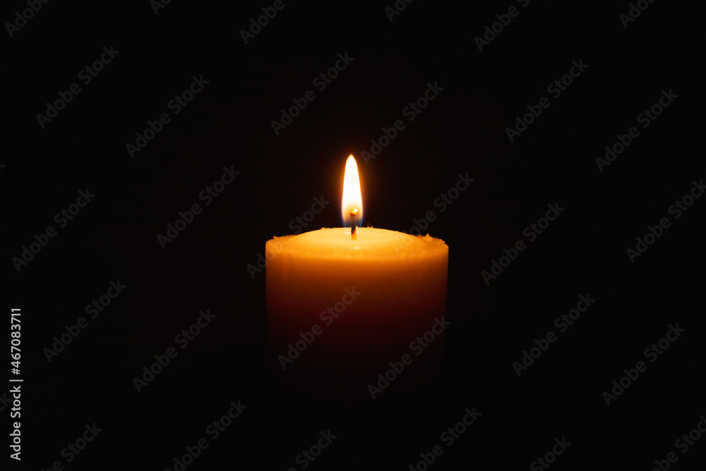 One single light candle burning brightly in the black background.Spiritual candle yellow flame. Flame of candle in the darkness.Copy space.