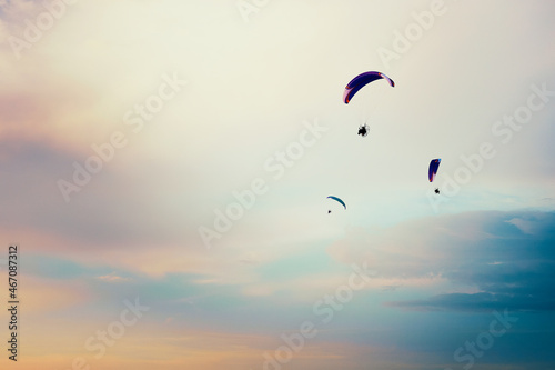 Paragliders flying in the sky. Paragliding in the cloudy colorful sky at sunset
