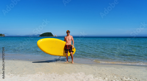 Active male surfer running with surfboard on sand beach enjoying healthy lifestyle extreme sport