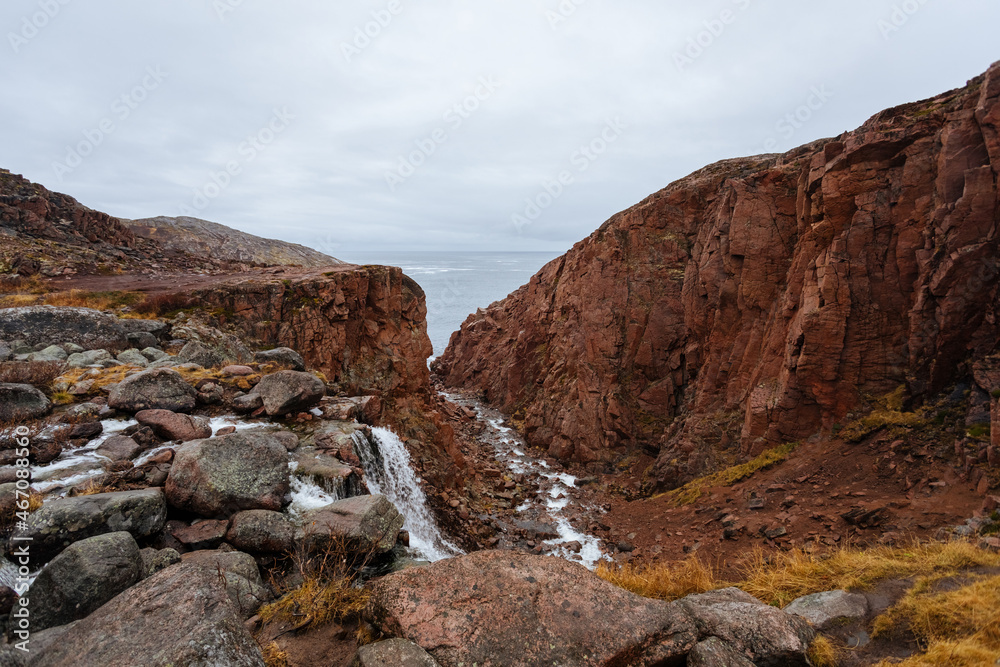 Rocks, a waterfall and the Barents Sea near the village of Teriberka