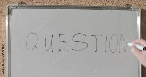 Hand writing the word QUESTION on white blackboard	