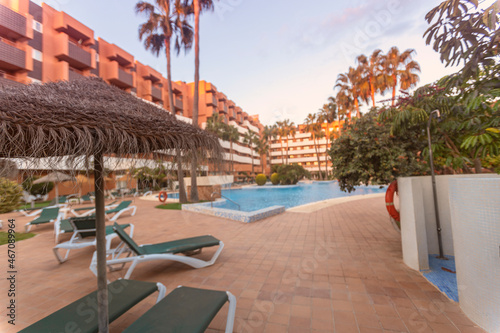 Photography of deck chair and umbrella and a pool, a residential area during the sunset with palms and pool