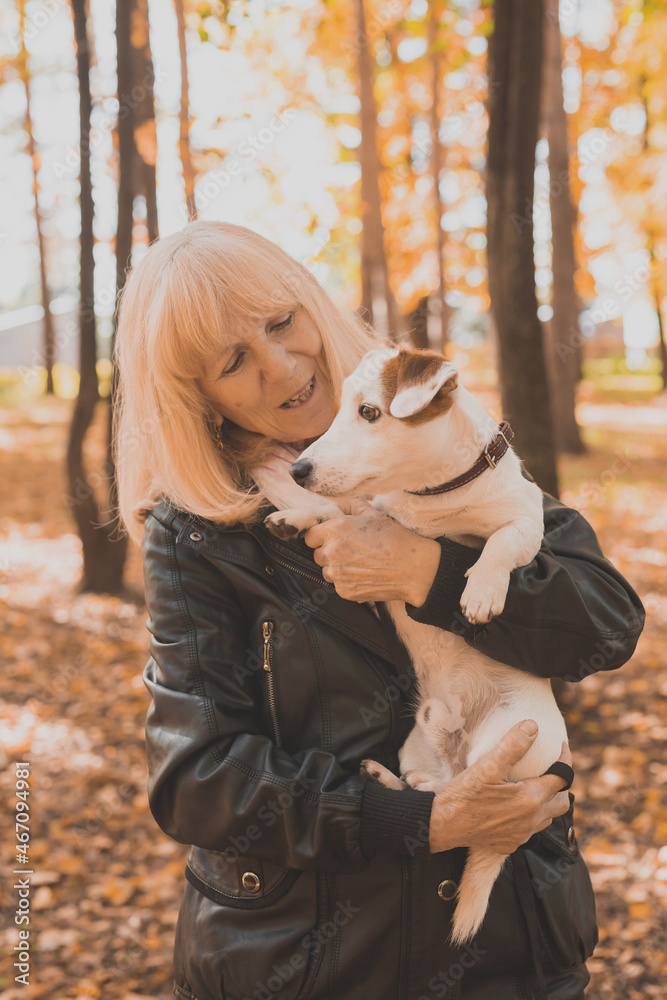 Senior smiling woman hugging her dog in autumn park. Active aging and pet concept. Senior smiling woman hugging her dog in autumn park. Active aging and pet concept.