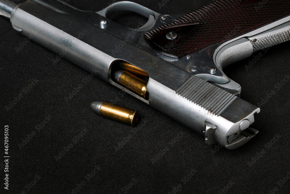 Automatic white gun stainless steel pistol weapon model m1911 with real bullet ammo head in black background Automatic white gun stainless steel pistol weapon model m1911 with real bullet ammo head in black background
