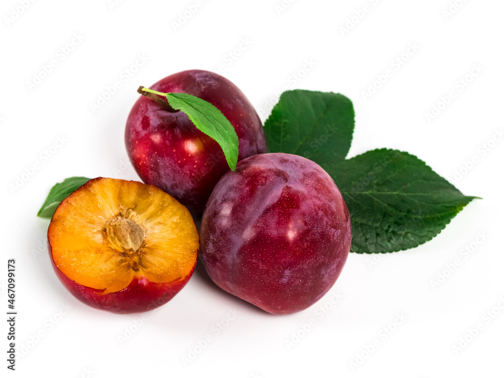 Ripe, juicy plums with green leaves on white background. Red plums in natural condition.