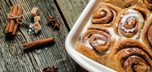 Cinnamon rolls with white cream sauce. Long banner format. top view photo