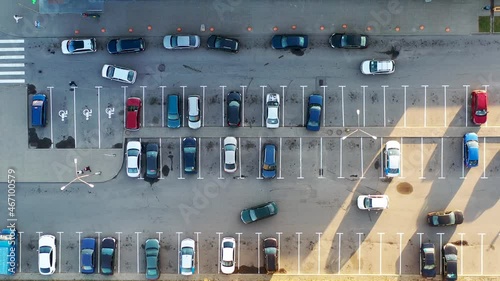 Aerial view of the parking lot near the store. Cars are parked in different places. People walk from cars to the store and back. People spend money in the store. View from above. 4K drone video.
