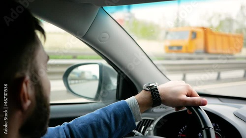 Young man in office clothes is driving a car. Concept of modern metropolis and business relations 