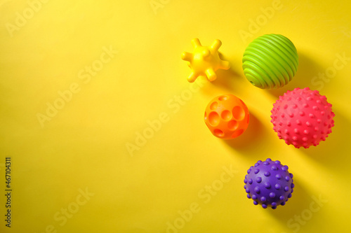 Multicolored rubber massagers for children, on a yellow background, place for an inscription