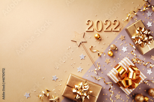Golden gift or present boxes with golden bows, 2022 numbers and confetti top view. Christmas and New Year background. Flat lay.