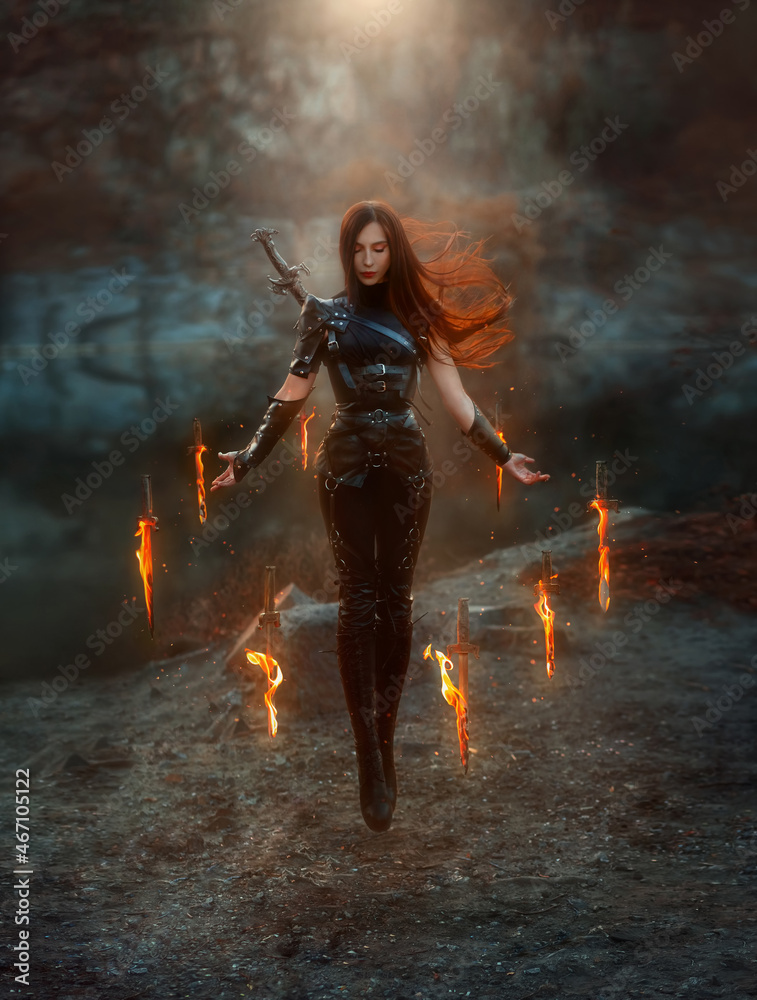 Naklejka premium Fantasy fighting woman assassin in levitation soars in air with burning daggers. Red-haired girl warrior in black leather costume. ninja soldier with knives, fire magic. Hair fluttering fly in wind